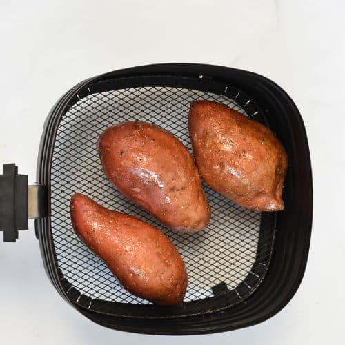 Cooked sweet potatoes in the basket of an air fryer.