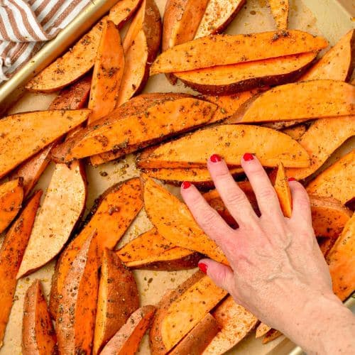 Coating sweet potato wedges with oil and seasoning.