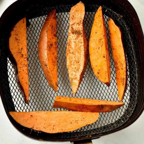 Potato wedges in the basket of an air fryer. 