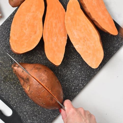 Halving sweet potatoes on a chopping board.