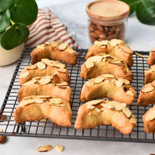 Baked almond croissant cookies cooling on a wire rack.