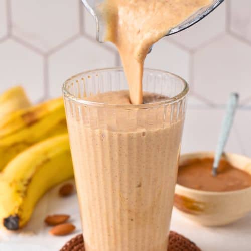 Pouring the Banana Almond Butter Smoothie into a tall glass.