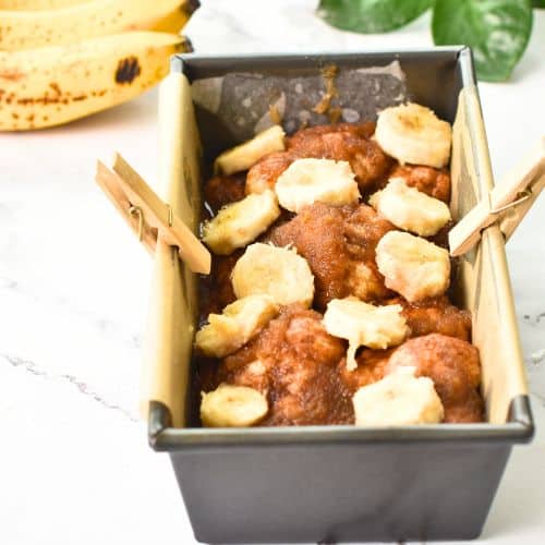 banana monkey bread decorated with banana slices in a loaf pan.