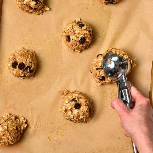 Releasing a Protein Oatmeal Cookie on a baking sheet with an ice cream scoop.