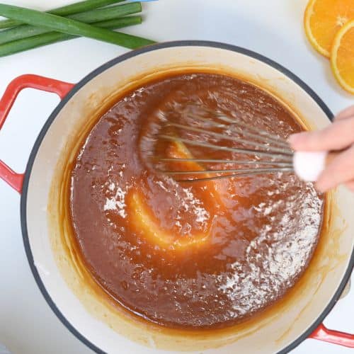 Stirring the orange sauce in a cast-iron pan.