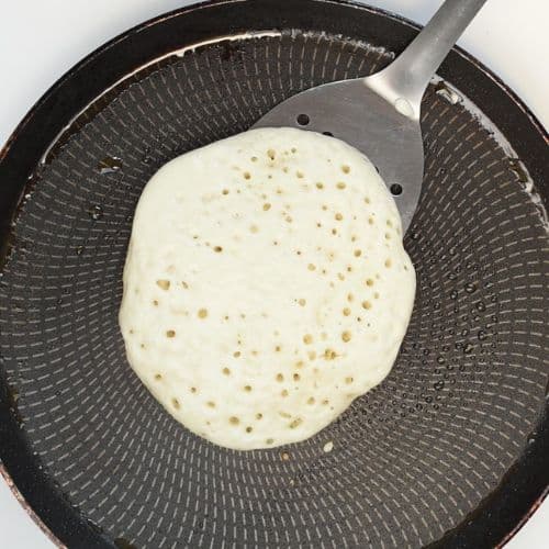 Spatula under a pancake on a crepe pan.