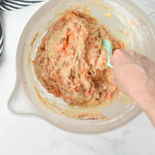 Stirring the vegan carrot cake banana bread batter with a silicone spatula.