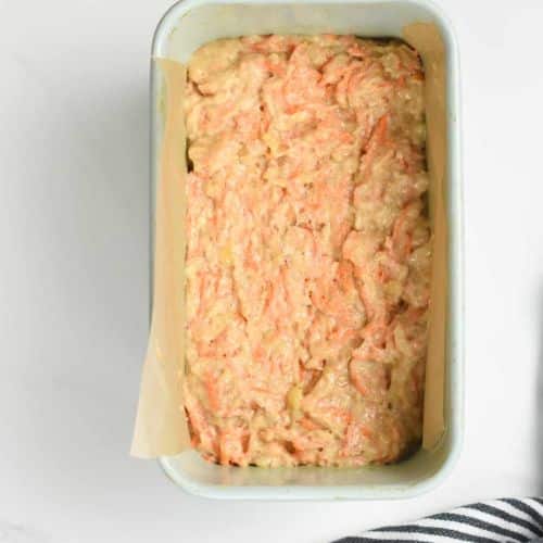 Vegan carrot cake banana bread batter in a loaf pan lined with parchment paper.