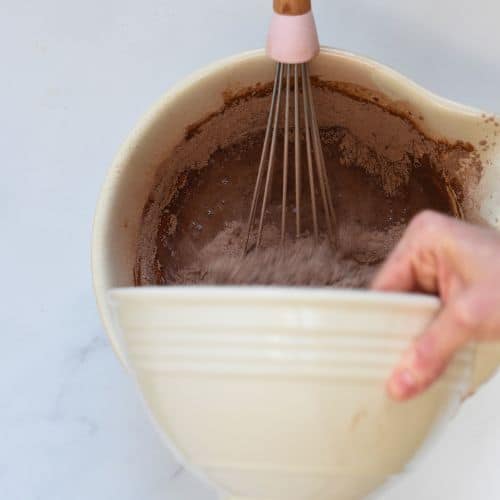 Pouring liquid ingredients in the dry vegan chocolate cupcake ingredients.
