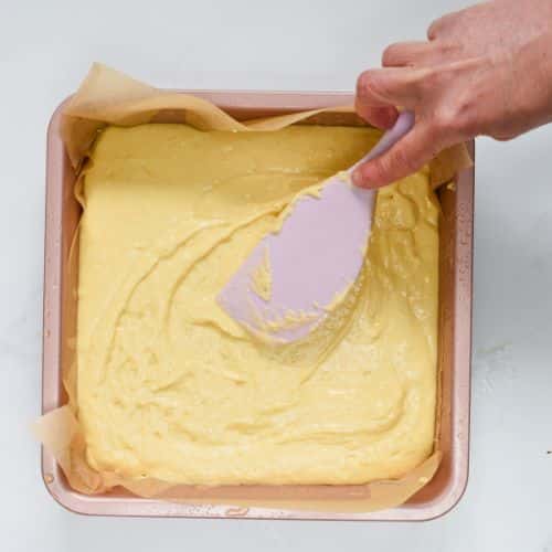 Spreading the vegan cornbread batter on a square baking pan.
