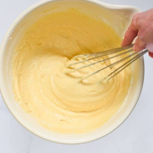 Whisking vegan cornbread batter in a large mixing bowl.
