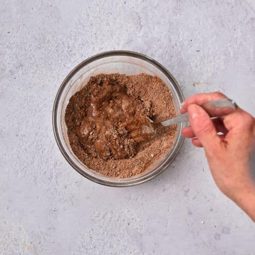 Stirring wet ingredients into dry Vegan Gluten-Free Mug Cake ingredients.