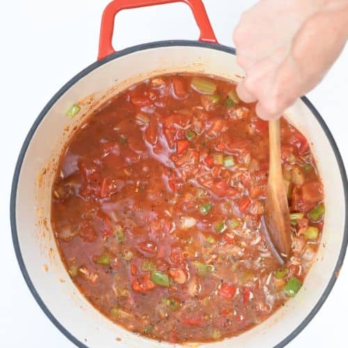 Stirring vegan jambalaya in a cast-iron pan.