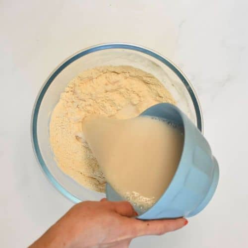 Pouring vegan buttermilk in the dry vegan protein pancake ingredients.