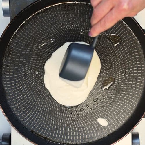 Pouring vegan protein pancake batter on a pan.