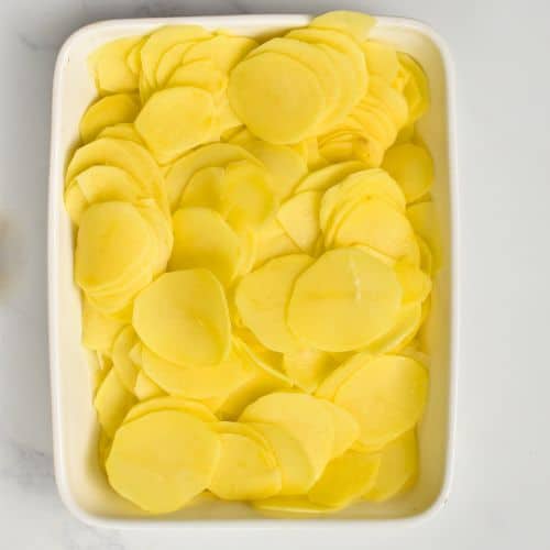 Potato slices assembled on a large ceramic dish.