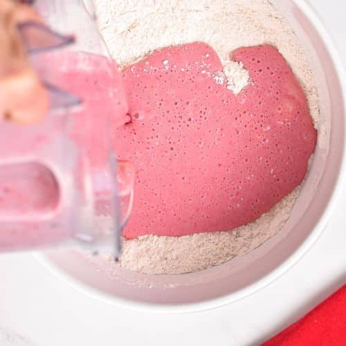 Pouring strawberry milk in the dry ingredients.