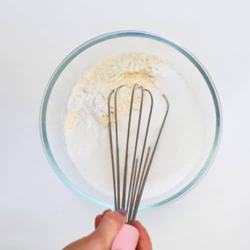 Stirring dry vegan cupcake ingredients in a bowl.