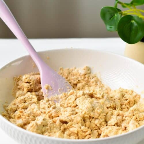 a pink rubber spatula stirring a peanut butter donut batter