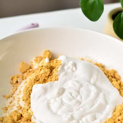 a mixing bowl filled with powdered peanut butter, yogurt, and self-rising flour