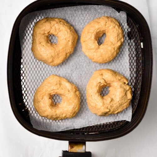 four Peanut Butter Donuts in a air fryer basket covered with parchment paper