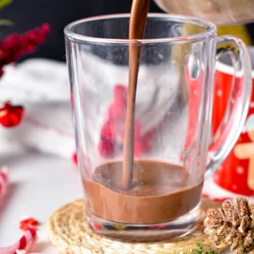 Pouring vegan peppermint hot chocolate into a glass mug.