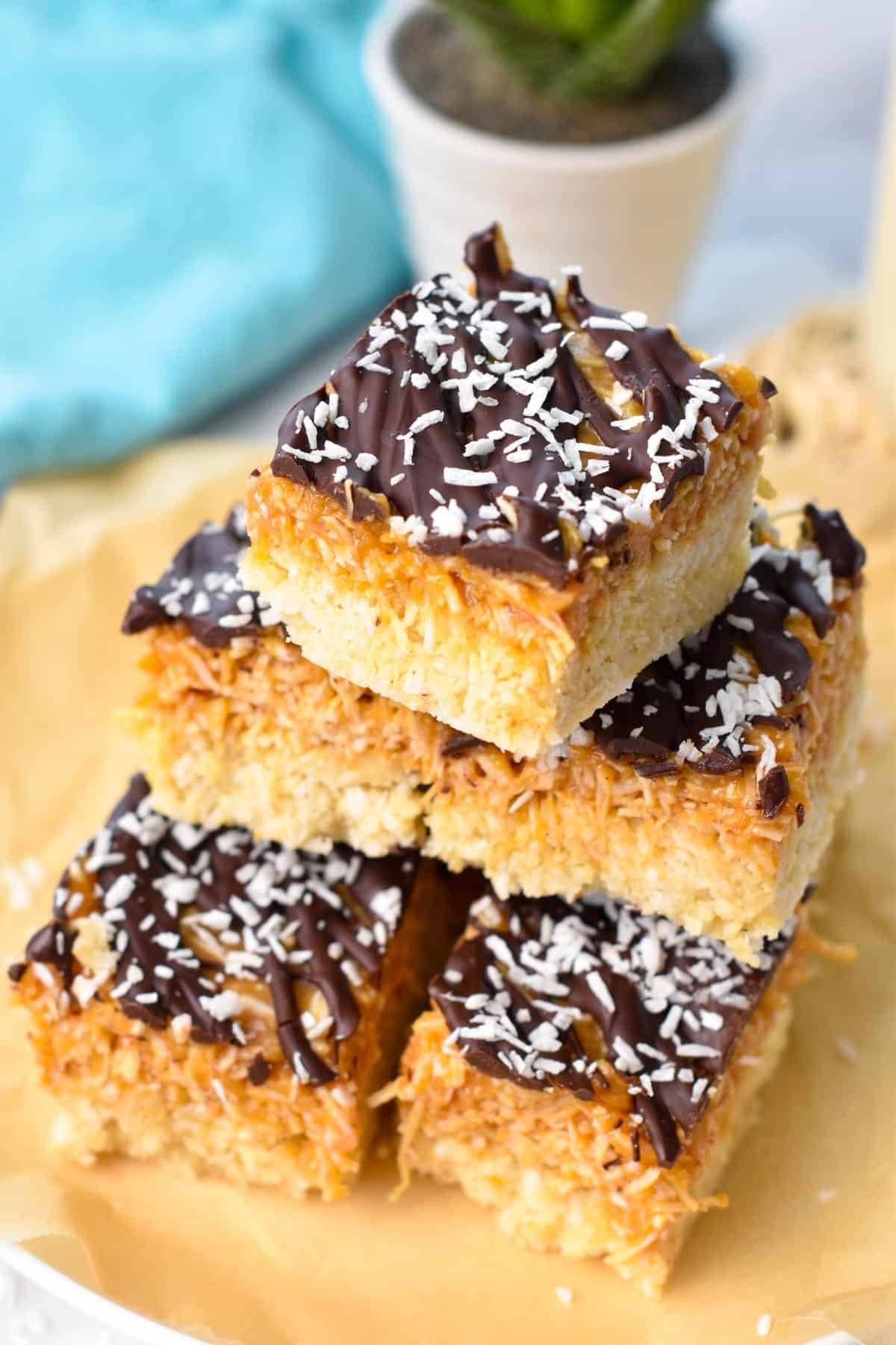 Samoa bars stacked on a plate with parchment paper.