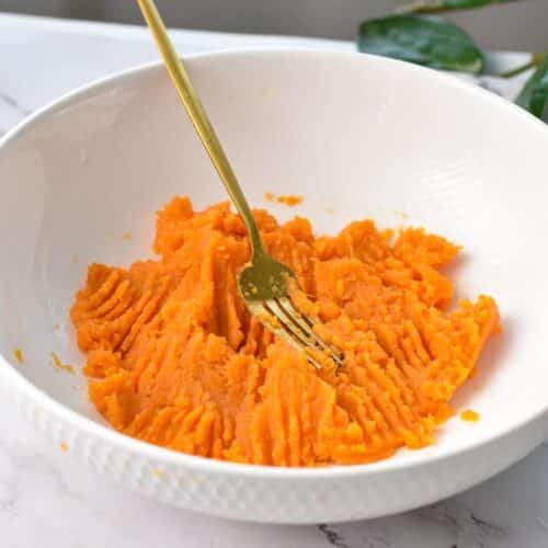 Sweet potato puree in a bowl with a golden fork.