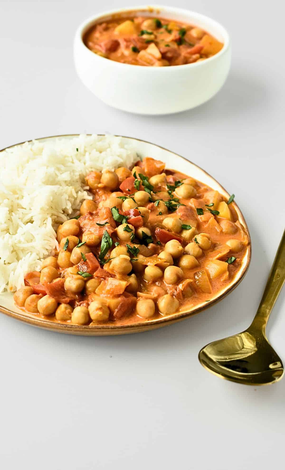 Vegan Chickpea Curry in a plate with rice next to a golden spoon.