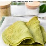 two spinach quinoa tortillas folded half way on a wooden chopping board covered with parchment paper
