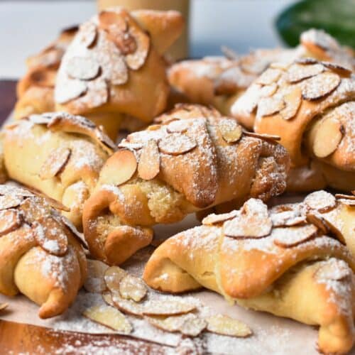 Almond Croissant Pastry stacked on a baking sheet.