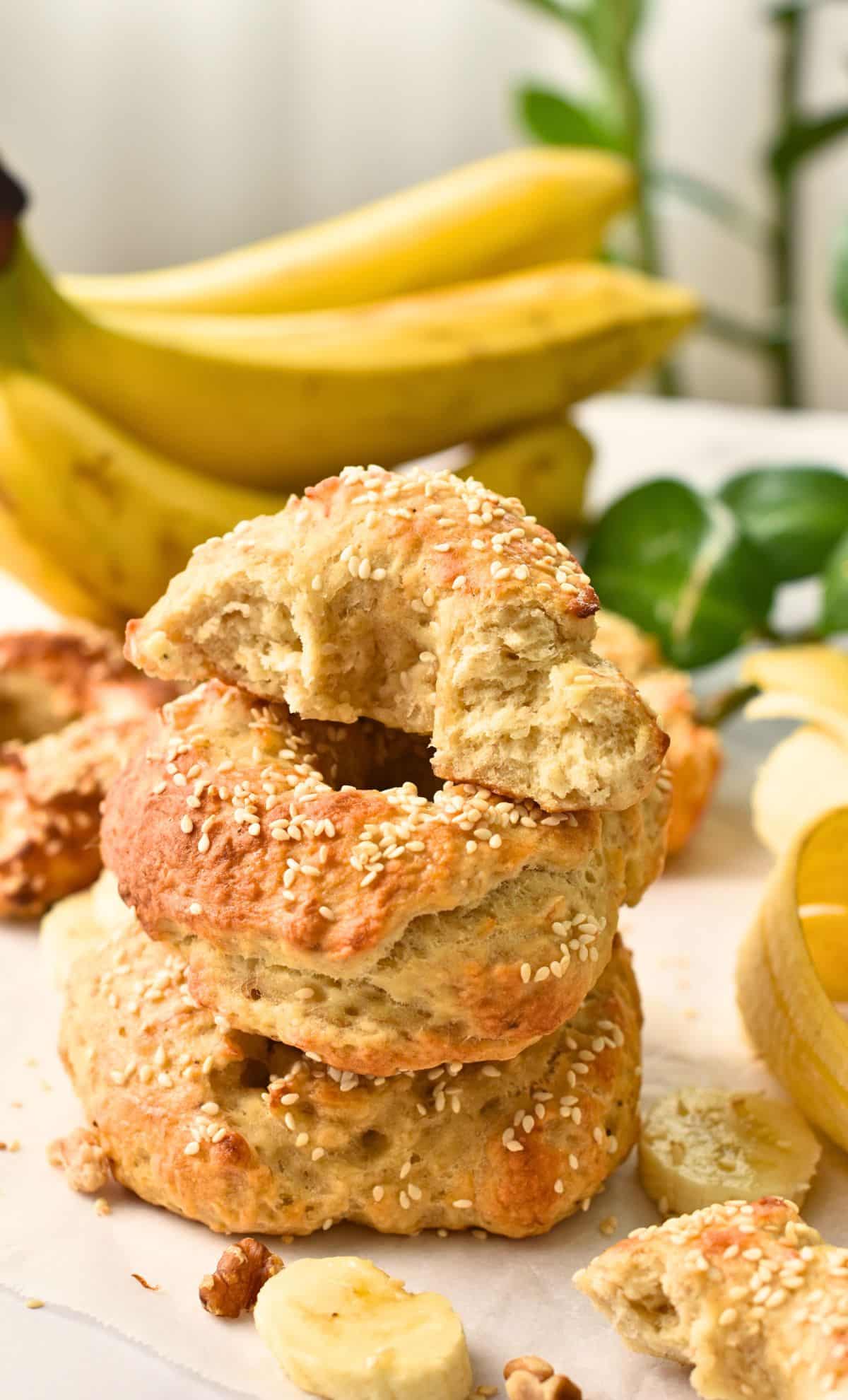 Banana Bagels stacked on a table with the top one sliced.