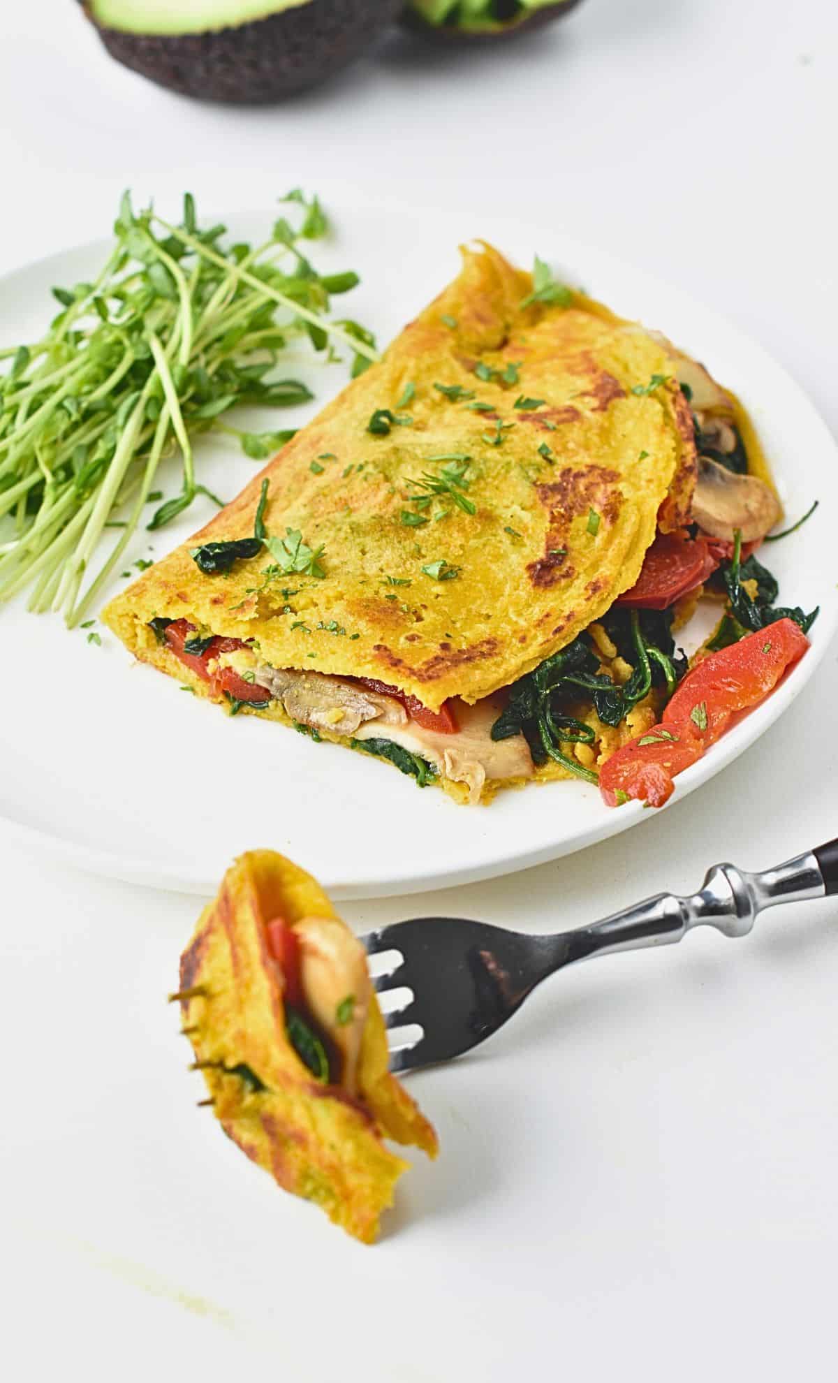 Chickpea flour omelette on a plate, filled with mushrooms, capsicum, and spinach.