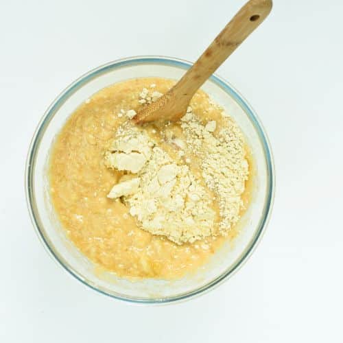 Mixing vegan cobbler batter in a mixing bowl with a wooden spoon.