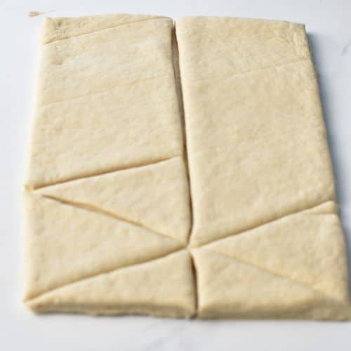 Cutting the Almond Croissant Pastry dough rectangle into small triangles.