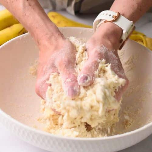 Kneading the banana tortilla dough with the hands in a large mixing bowl.