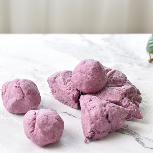 Rolling purple pita dough into small balls.