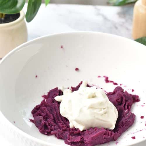 Purple sweet potato in a mixing bowl with vanilla yogurt on top.