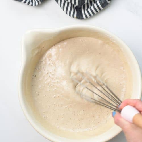 Whisking vegan buckwheat crepe batter in a mixing bowl.