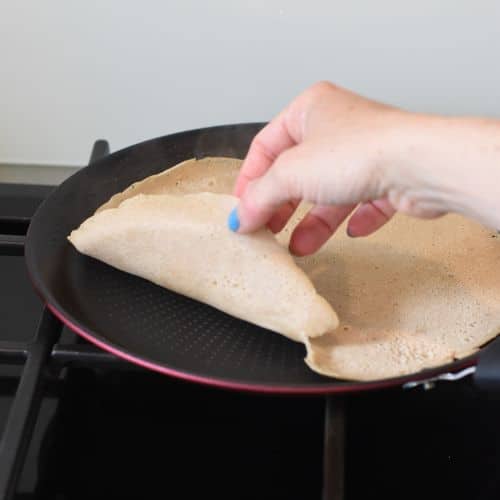 Checking the cooking of a vegan buckwheat crepe.