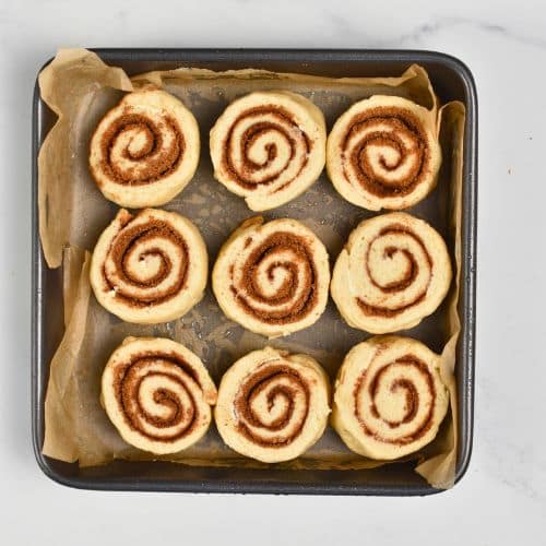 Sliced Yeast-Free Cinnamon Rolls placed on a square pan with parchment paper.