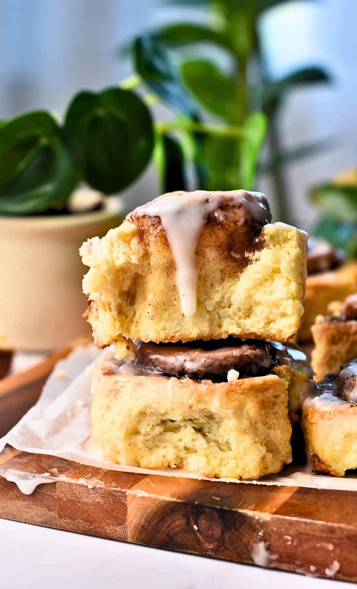 Yeast-Free Cinnamon Rolls stacked on a wooden board with the top one sliced.