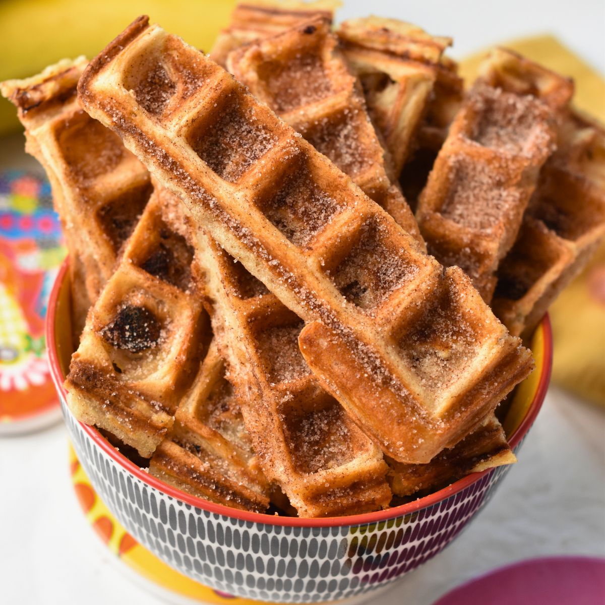Banana Churros Waffles stacked on a small bowl.