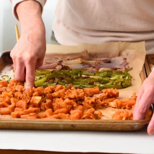 Mashing baked sweet potato on a baking sheet.