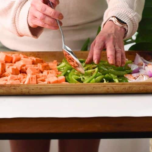 Spreading oil and taco seasoning on vegetables in a baking pan.