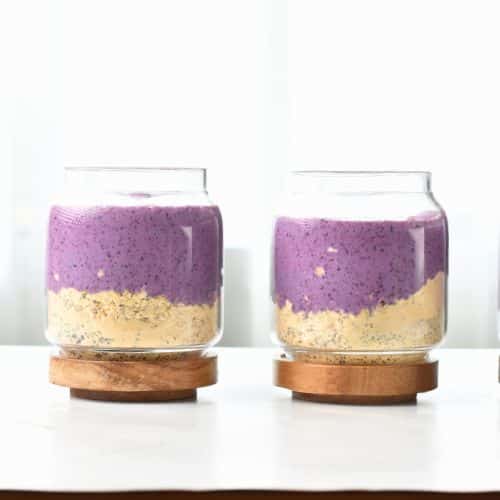 Blueberry milk added to oats and protein powder in glass jars.