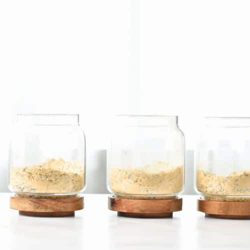 Oats and protein powder in three glass jars.