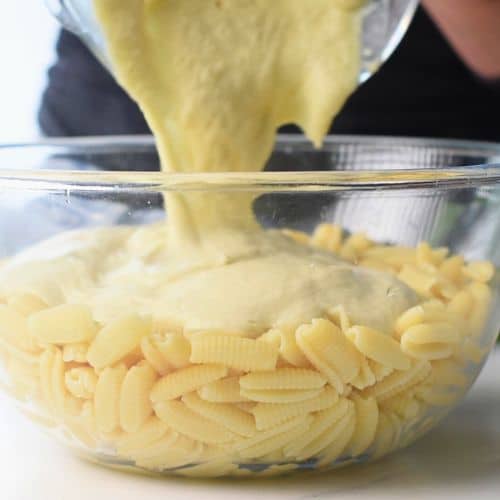 Pouring cauliflower sauce on top of cooked pasta.