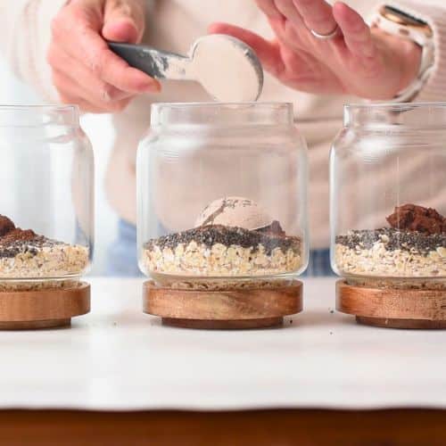 Adding Three jars with Chocolate Peanut Butter Protein Overnight Oats ingredients to jars.