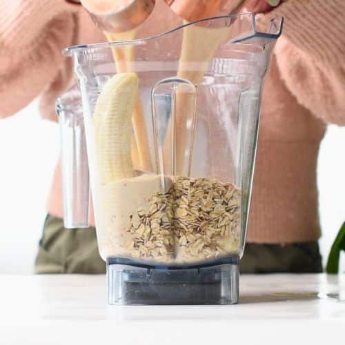 Pouring liquid Protein Baked Oats ingredients in a blender.